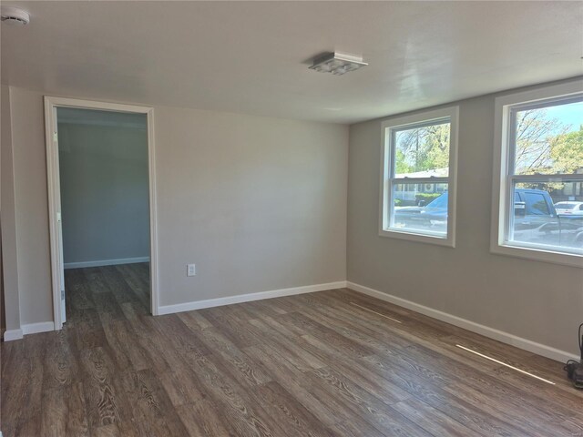spare room with baseboards, dark wood-style flooring, and plenty of natural light