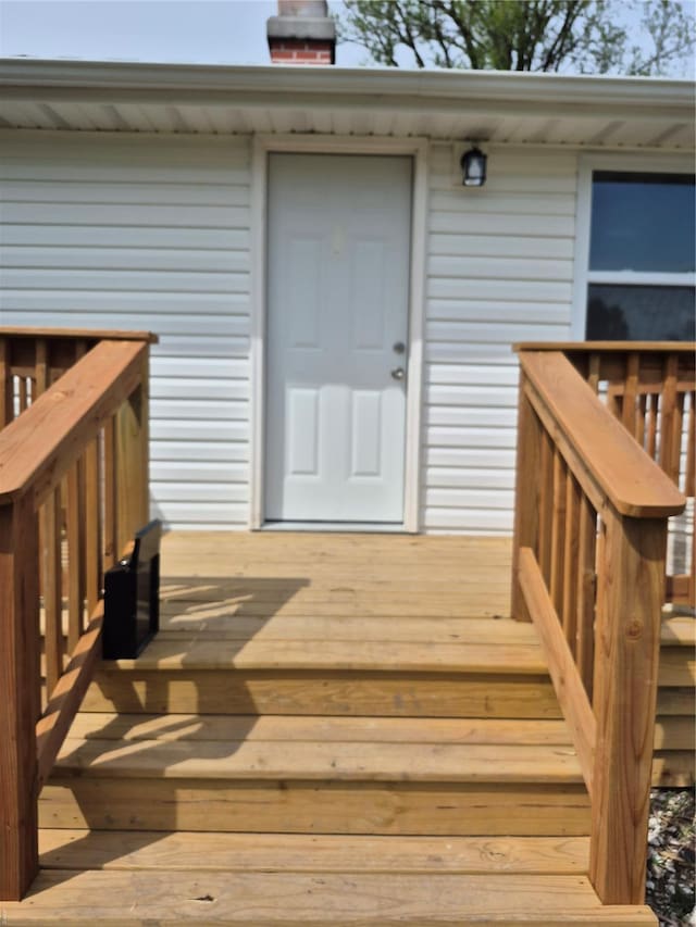 entrance to property featuring a chimney and a deck