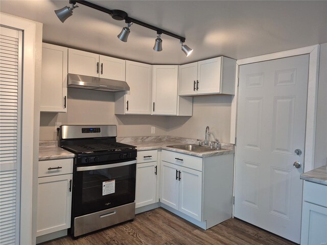 kitchen featuring dark wood-style floors, stainless steel gas range oven, under cabinet range hood, a sink, and white cabinetry