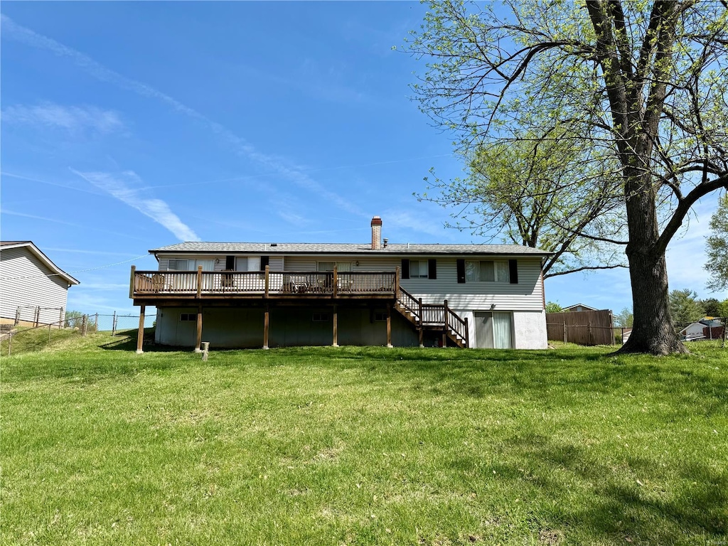 rear view of property with a wooden deck, a lawn, stairs, and fence