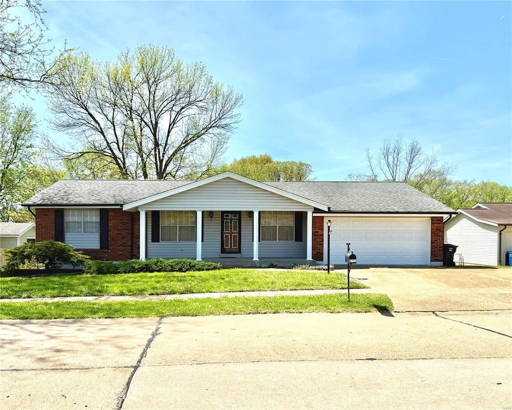 ranch-style house featuring a front lawn, brick siding, driveway, and a garage