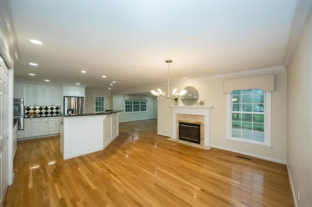 kitchen with dark countertops, appliances with stainless steel finishes, tasteful backsplash, an inviting chandelier, and ornamental molding