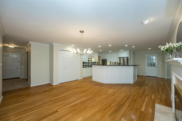 kitchen with crown molding, dark countertops, light wood-style flooring, appliances with stainless steel finishes, and a notable chandelier