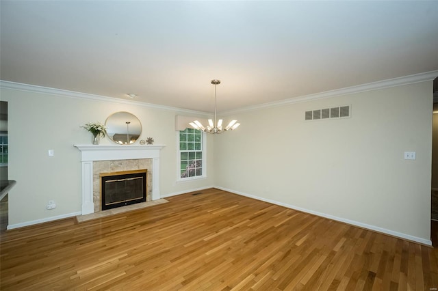 unfurnished living room featuring visible vents, crown molding, baseboards, an inviting chandelier, and a premium fireplace