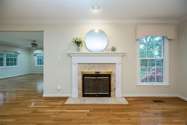 details with ceiling fan, visible vents, a tiled fireplace, and wood finished floors