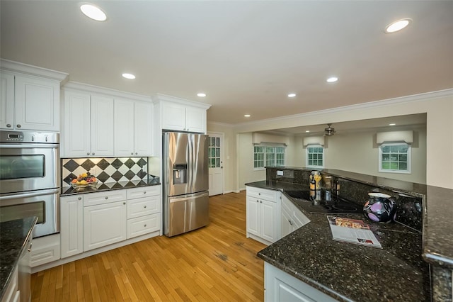 kitchen with ornamental molding, an AC wall unit, white cabinets, light wood finished floors, and appliances with stainless steel finishes