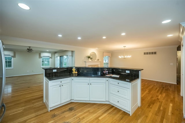 kitchen featuring white cabinets, visible vents, ornamental molding, and light wood finished floors