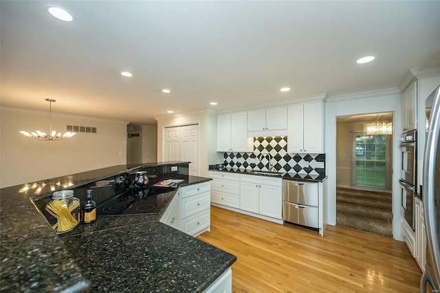 kitchen featuring crown molding, decorative backsplash, white cabinets, and a notable chandelier