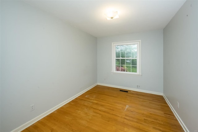 spare room with baseboards, visible vents, and light wood finished floors