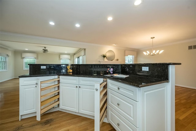 kitchen featuring an inviting chandelier, ornamental molding, white cabinetry, and a wealth of natural light