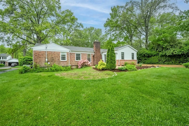 view of front of home with a chimney, a front yard, and brick siding