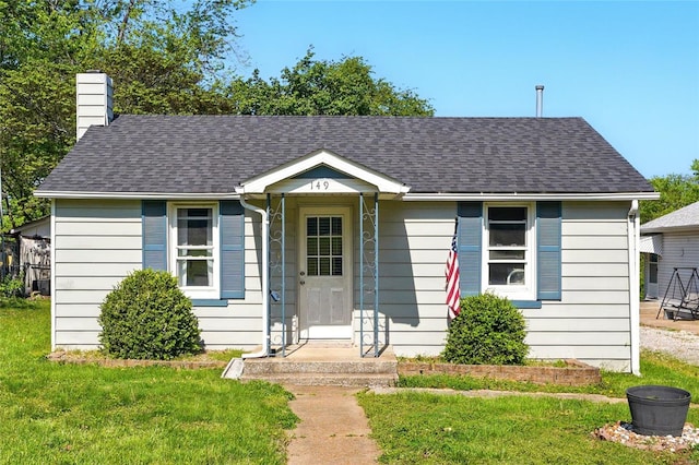 bungalow with a chimney, a shingled roof, and a front yard