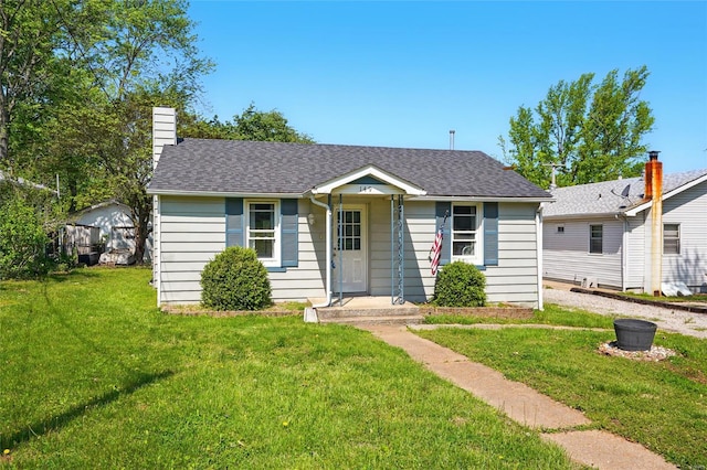 view of front of home with roof with shingles, a chimney, and a front yard