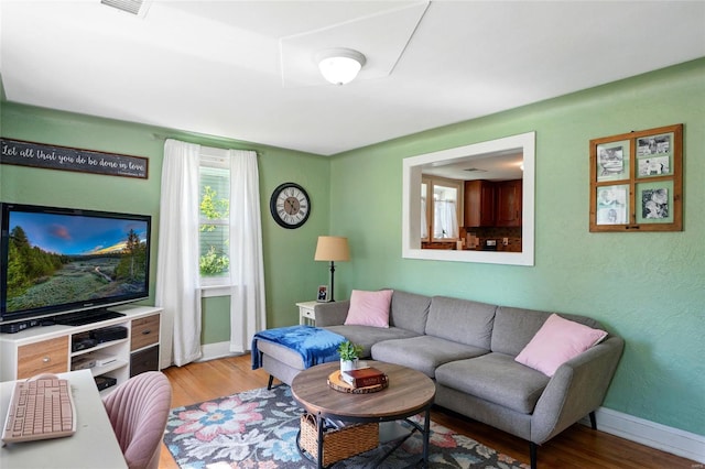 living area featuring baseboards, wood finished floors, and visible vents