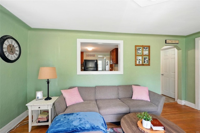 living area featuring baseboards, arched walkways, and wood finished floors