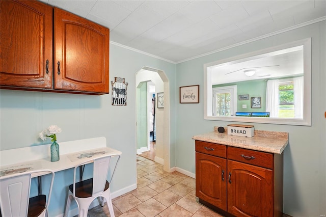 laundry room with arched walkways, baseboards, ornamental molding, and light tile patterned floors