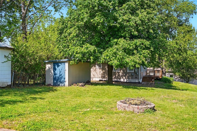view of yard with an outdoor structure, a fire pit, a shed, and a wooden deck