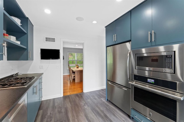 kitchen featuring blue cabinets, stainless steel appliances, dark wood-style floors, and visible vents