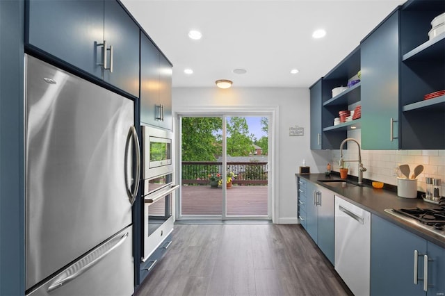 kitchen with open shelves, appliances with stainless steel finishes, a sink, and blue cabinetry