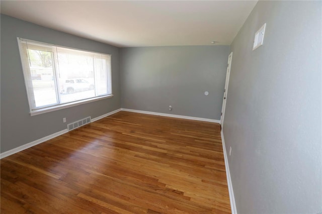 unfurnished room featuring visible vents, wood finished floors, and baseboards