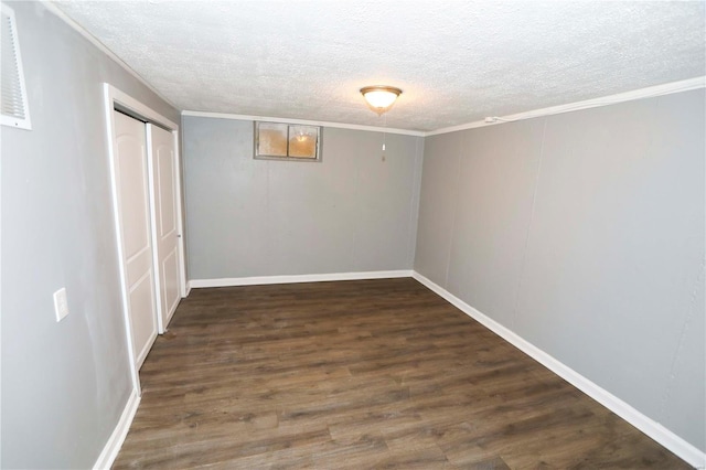 interior space featuring a textured ceiling, wood finished floors, baseboards, and ornamental molding