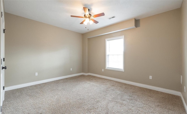 spare room with carpet flooring, ceiling fan, visible vents, and baseboards