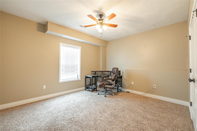 carpeted office space featuring baseboards, visible vents, and ceiling fan