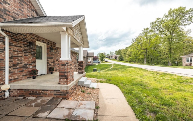view of home's exterior featuring covered porch, a lawn, and brick siding