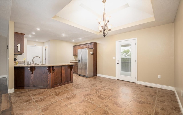 kitchen with a notable chandelier, recessed lighting, baseboards, a peninsula, and stainless steel refrigerator with ice dispenser