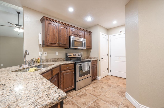 kitchen with light stone counters, a sink, stainless steel appliances, a ceiling fan, and recessed lighting