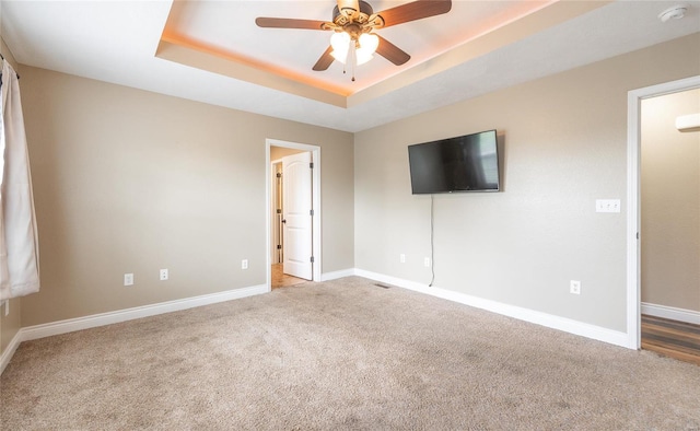 interior space featuring baseboards, ceiling fan, and a tray ceiling