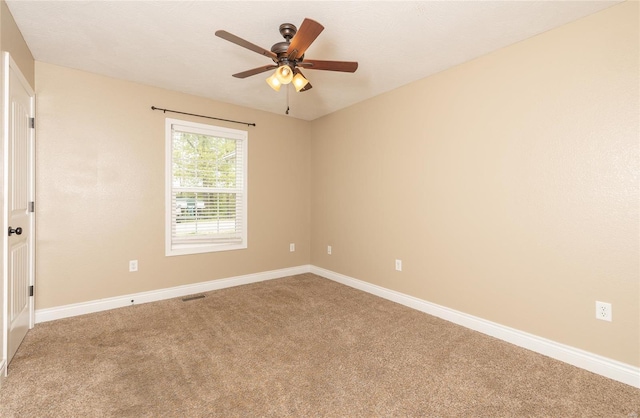 carpeted spare room featuring baseboards, ceiling fan, and visible vents