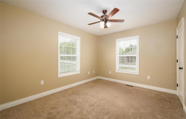 spare room featuring visible vents, carpet, baseboards, and a wealth of natural light