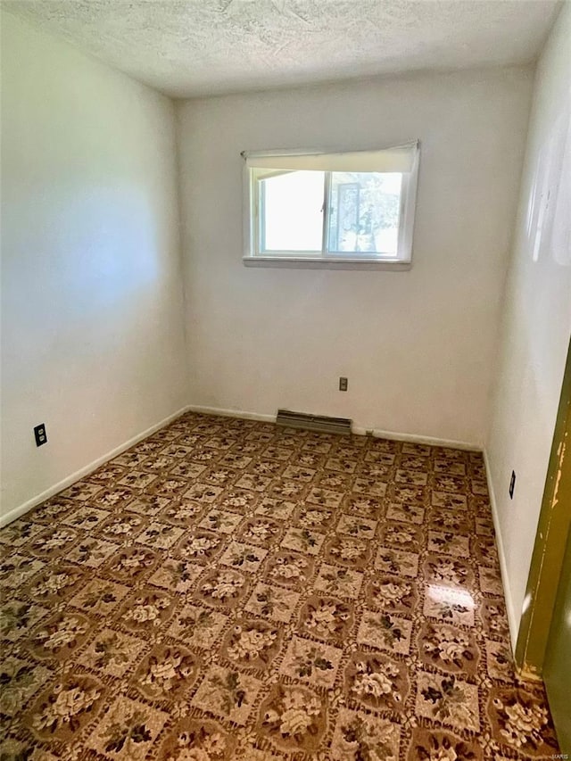 empty room with baseboards, a textured ceiling, and visible vents