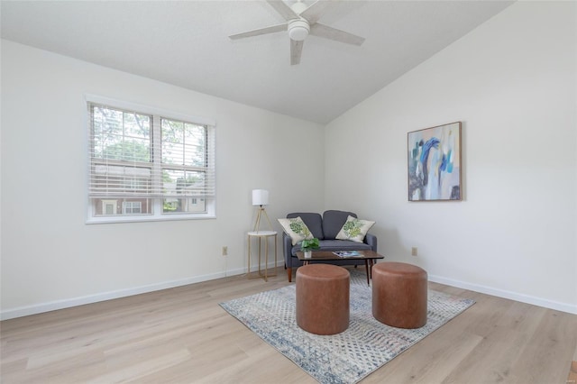 living area with baseboards, ceiling fan, vaulted ceiling, and light wood-type flooring