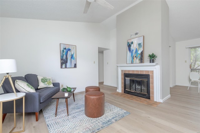 living room featuring a ceiling fan, visible vents, a fireplace, wood finished floors, and baseboards