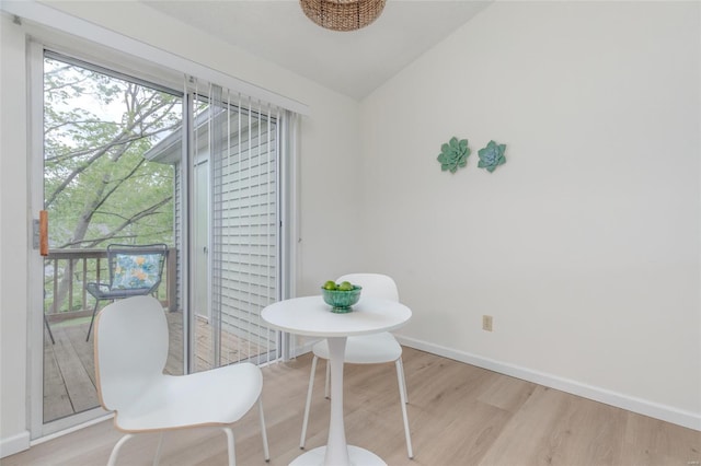 dining area featuring baseboards, lofted ceiling, wood finished floors, and a wealth of natural light