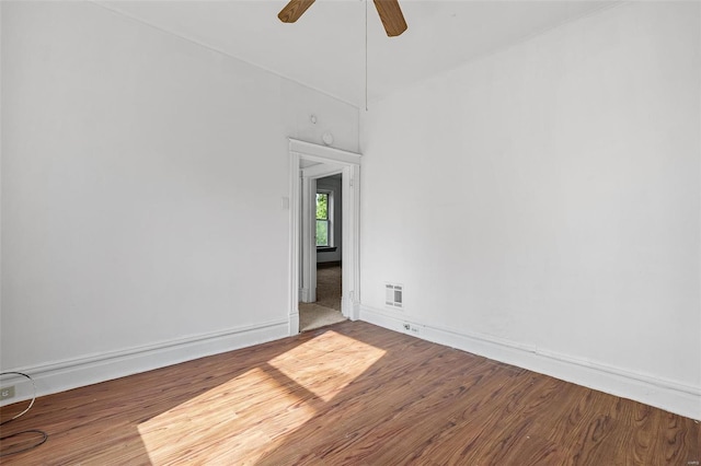 spare room featuring baseboards, ceiling fan, visible vents, and wood finished floors