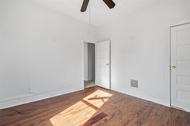 spare room with visible vents, a ceiling fan, baseboards, and wood finished floors