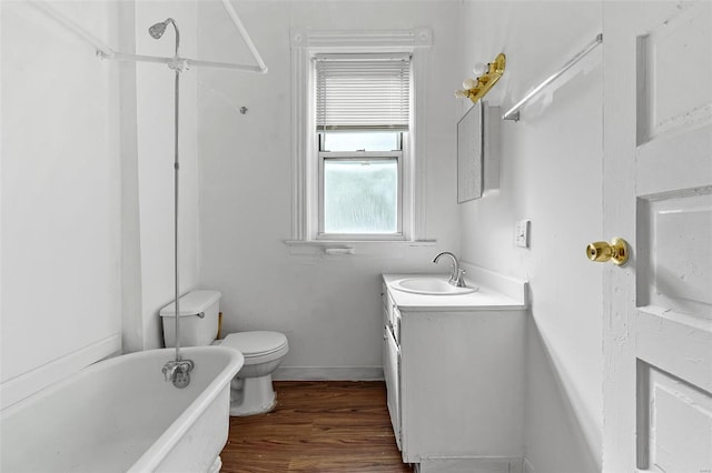 bathroom with wood finished floors, vanity, baseboards, toilet, and a soaking tub