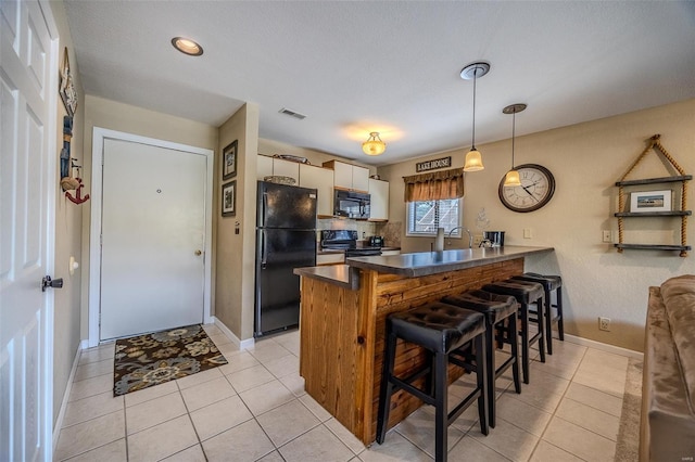 kitchen with light tile patterned floors, a breakfast bar, black appliances, and a peninsula
