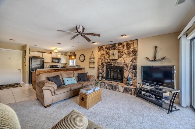 living area featuring visible vents, a fireplace, ceiling fan, light colored carpet, and a wealth of natural light