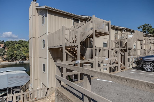 view of property with stairs and uncovered parking
