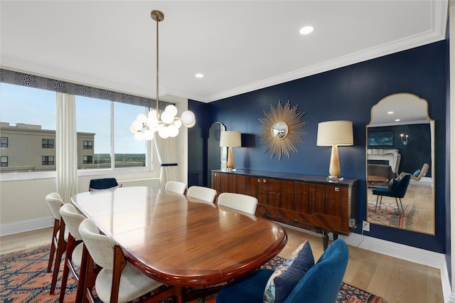 dining area featuring a fireplace, wood finished floors, baseboards, a chandelier, and ornamental molding
