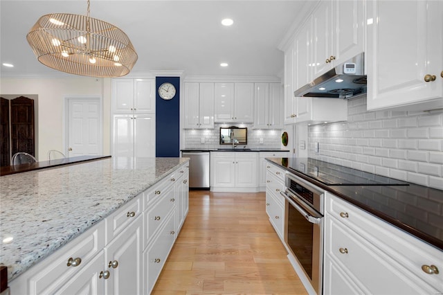 kitchen featuring stainless steel appliances, white cabinets, under cabinet range hood, and a notable chandelier