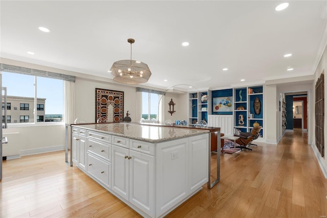 kitchen featuring white cabinets, an inviting chandelier, baseboards, a kitchen island, and ornamental molding