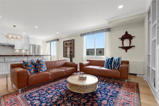 living area featuring recessed lighting, ornamental molding, light wood-style flooring, and an inviting chandelier