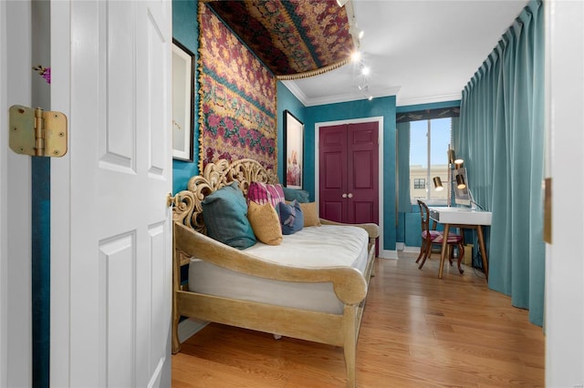 bedroom featuring light wood-type flooring, baseboards, and crown molding