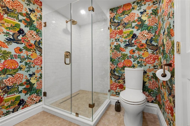 bathroom with toilet, baseboards, and a shower stall