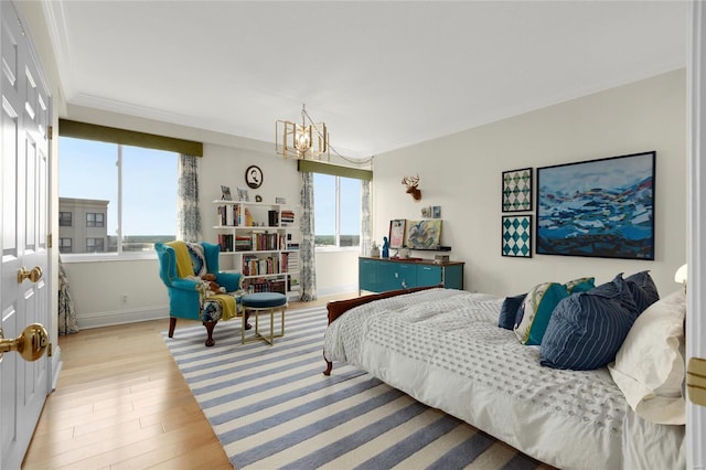 bedroom with an inviting chandelier, multiple windows, ornamental molding, and light wood-type flooring